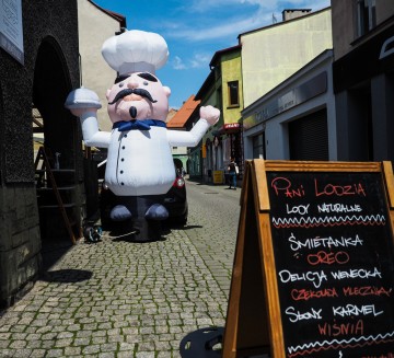 Hello Man Kucharz zapraszający gości do restauracji i skradający spojrzenia przechodniów.